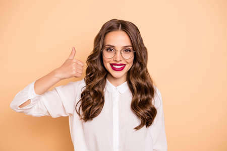 Close-up portrait of her she nice-looking attractive lovely perfect glamorous gorgeous content glad cheerful cheery wavy-haired lady showing thumbup ad isolated over beige pastel backgroundの写真素材