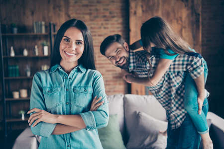 Portrait of charming woman with her arms crossed smiling and people piggy-backing wearing plaid denim jeans shirt t-shirt indoorsの写真素材
