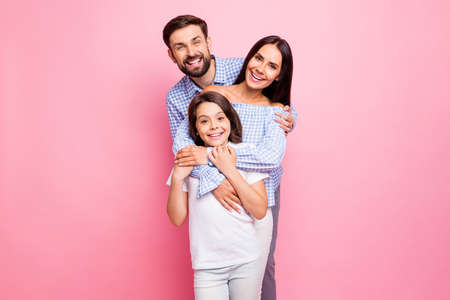 Portrait of cheerful family cuddling smiling wearing checkered plaid shirt off-shoulders white t-shirt isolated over pink backgroundの写真素材