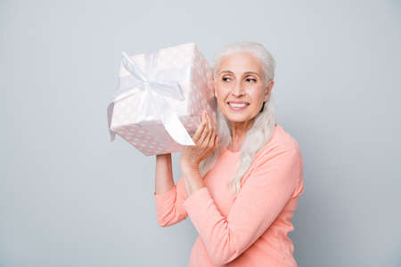 Photo of pretty nice attractive friendly sincere kind granny holding big giftbox trying to guess...