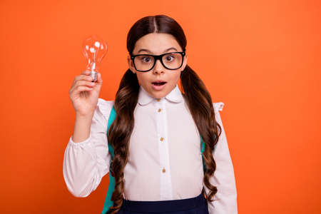 Close up photo astonished people kid have thoughts light bulb thoughtful creative, clever geek white blouse shirt tails eyewear eyeglasses rucksack isolated stylish she her orange backgroundの写真素材