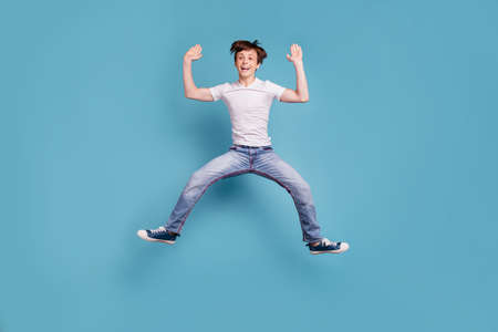 Full length body size photo of boy preparing to do splits right in air while isolated with blue backgroundの写真素材