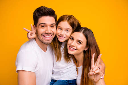 Close-up portrait of three nice attractive charming cute lovely cheerful cheery optimistic person spending weekend showing v-sign isolated over bright vivid shine yellow backgroundの写真素材