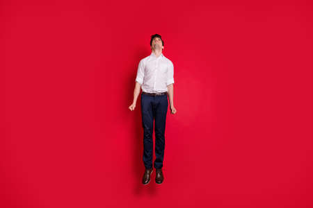 Full length body size photo of white, businessman wearing pants jumping up career stairs while isolated with red backgroundの写真素材