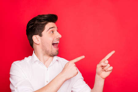 Close-up portrait of his he nice cheerful cheery amazed guy office employee pointing two forefingers aside ad advert novelty black Friday isolated on bright vivid shine red backgroundの写真素材