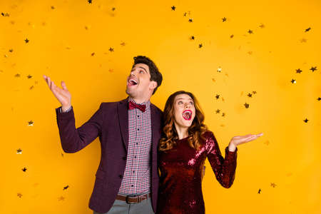 Portrait of impressed millennial raise hands meeting see confetti scream shout dress suit tux tuxedo wavy curly hairdo isolated over yellow backgroundの写真素材