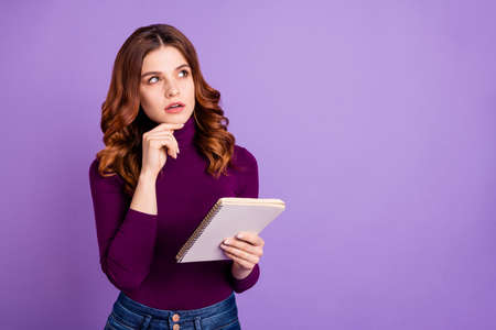 Portrait of concentrated youth hold hand wear denim jeans isolated over purple backgroundの写真素材