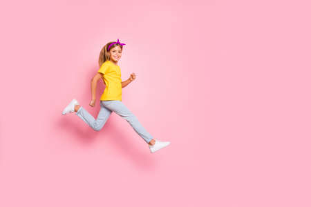 Full length body size view of her she nice attractive lovely cheerful cheery pre-teen girl wearing yellow t-shirt running marathon isolated over pink backgroundの写真素材