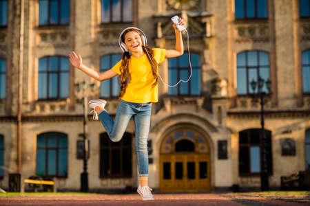 Full length body size view of nice attractive charming cute lovely cheerful cheery careless wavy-haired girl having fun rest relax using mp3 player in the street park town outsideの写真素材