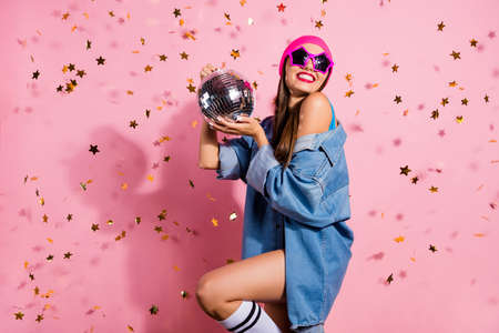 Portrait of elegant party youth holding mirror ball wearing denim jeans jacket eyewear eyeglasses isolated over pink backgroundの写真素材
