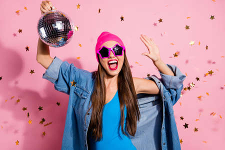 Close up photo of cheerful woman in eyeglasses eyewear holding mirror ball showing her palm wearing blue body suit isolated over pink backgroundの写真素材