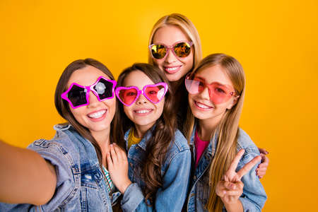 Closeup photo portrait of beautiful brunette blonde haired ladies people youth showing peace v-sign taking selfie on summer holiday isolated vivid yellow backgroundの写真素材