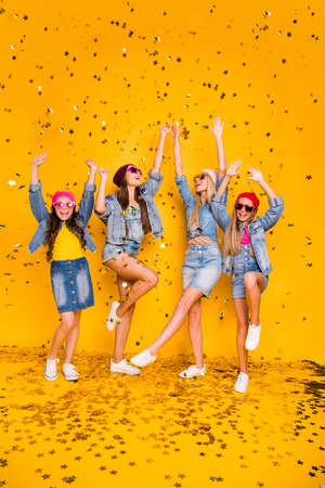 Vertical full length size body photo of four beautiful cheerful ecstatic excited positive charming people girlfriends having funky fancy vacation and rest chilling out isolated yellow backgroundの写真素材