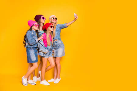 Full body photo of four cool confident charming nice glad funky in blonde brunette denim glamorous clothes girlfriend mom baddies fellows making self picture isolated yellow background with copyspaceの写真素材
