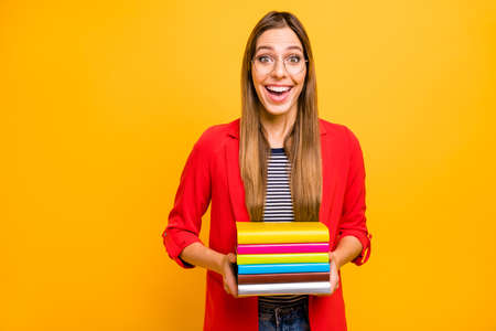 Portrait of astonished lady holding fiction books screaming wow omg wearing eyeglasses eyewear isolated over yellow backgroundの写真素材