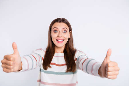 Crazy lady raising thumbs up approving good quality of product wear striped pullover isolated white backgroundの写真素材