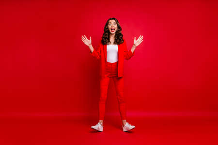 Full body photo of impressed person screaming raising her hands hearing news isolated over red backgroundの写真素材