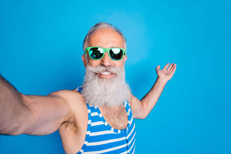 Close up photo of retired man in eyeglasses eyewear holding his palm making selfie wearing striped...