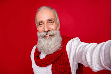 Self-portrait of his he nice attractive well-groomed confident content cheerful gray-haired man grandpa isolated over bright vivid shine red backgroundの写真素材