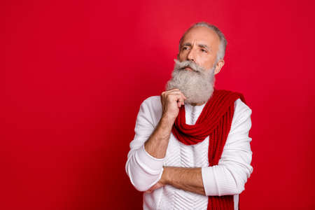 Portrait of his he nice attractive doubtful gray-haired man touching beard thinking creating decision isolated over bright vivid shine red backgroundの写真素材