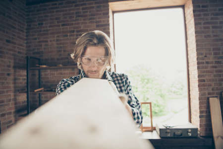 Portrait of his he nice attractive handsome, blond focused serious guy skilled artisan builder looking checking smooth surface at industrial brick loft style interior workplaceの写真素材