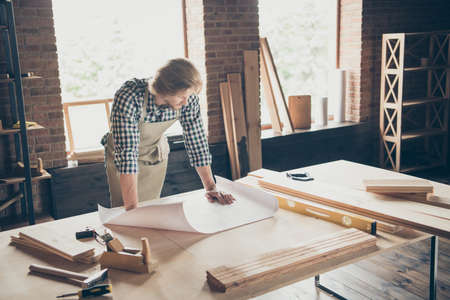 Portrait of his he nice attractive handsome blond focused guy artisan builder reading drafts, creating projects at industrial brick loft style interior indoors workplace studioの写真素材