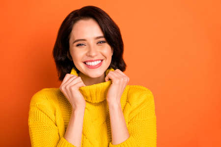 Close up photo of charming, gorgeous woman being photographed wearing yellow sweater while isolated with orange backgroundの写真素材