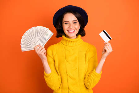 Photo of cheerful trendy excited nice girl proud to have earned considerable amount of money while isolated with orange backgroundの写真素材