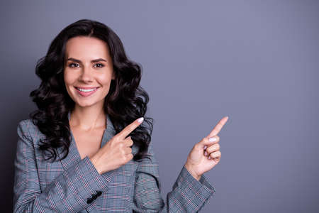 Close photo of pretty lady looking with toothy smile showing promo ads wearing blazer jackets isolated over gray backgroundの写真素材