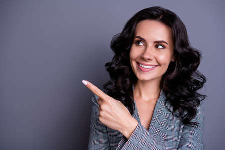 Close up photo of beautiful lady looking pointing her finger at copy space showing promo wearing suit blazer jacket isolated over grey backgroundの写真素材