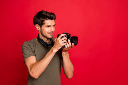 Photo of amazing guy with photo digicam making pictures wear casual grey t-shirt isolated on red backgroundの写真素材