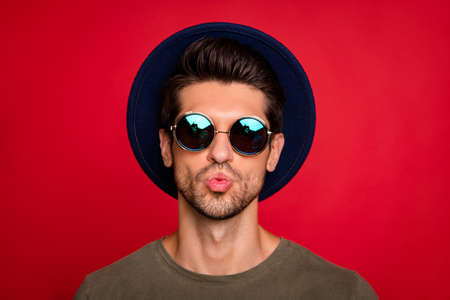 Photo of macho guy sending air kiss girlfriend wear vintage hat sun specs and grey t-shirt isolated on red backgroundの写真素材