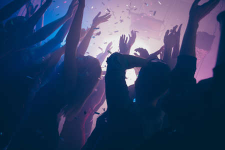 Close up photo of many people dancing clubbing purple lights confetti fog nightclub hands raised formal-wear clothes outfitの写真素材