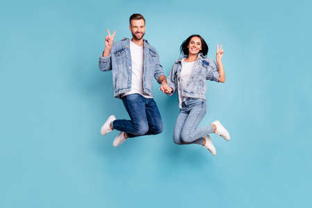 Photo of nice charming cheerful enjoying two people shoiwng you v-sign jumping after having gone on...