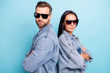 Close up photo of undercover agents spy in eyewear eyeglasses standing back to back wearing jeans denim jackets isolated over blue backgroundの写真素材