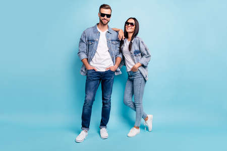 Full length photo of charming spouses looking with beaming smile wearing denim jeans eyeglasses eyewear isolated over blue backgroundの写真素材