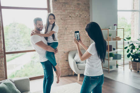 Portrait of nice attractive lovely adorable cheerful cheery friendly family in casual white t-shirts jeans mommy taking making photo at industrial loft style interior living-room indoorsの写真素材