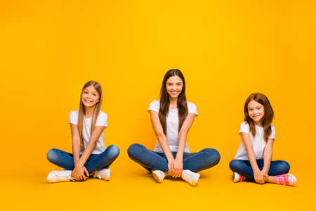 Photo of amazing different age ladies sitting floor with crossed legs wear casual clothes isolated...