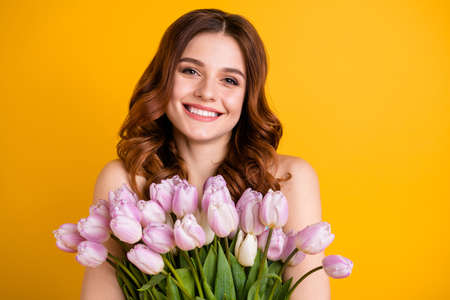 Close up photo of amazing lady holding big bunch of pink tulips in hands isolated yellow backgroundの写真素材
