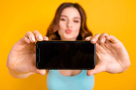 Photo of lady holding telephone making self photos with coquette kisses wear tank-top isolated yellow backgroundの写真素材