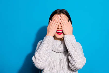 Petty funny lady hiding eyes playing seeking wear knitted pullover isolated blue backgroundの写真素材