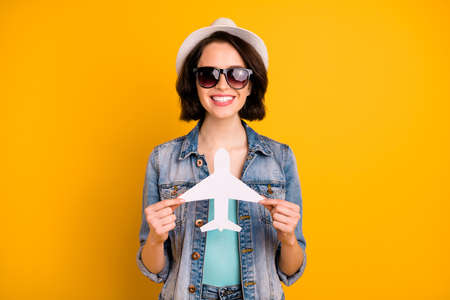 Photo of cheerful nice cut charming pretty kind friendly girl showing you small plane wearing cap...