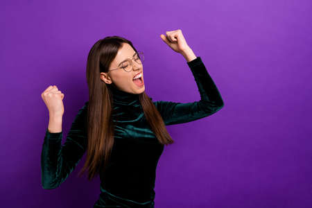 Portrait of delighted lady raising her hands fists shouting yeah wearing eyeglasses eyewear isolated over purple violet backgroundの写真素材