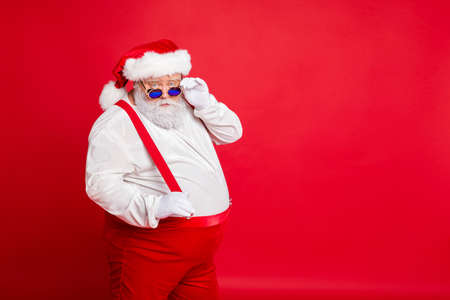 Portrait of handsome old funny fat overweight santa claus with big belly touch his retro specs...