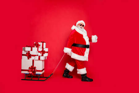 Full length body size view of generous kind funky fat overweight plump gray-haired bearded man carrying many pile stack cool purchases winter tradition isolated over bright vivid shine red backgroundの写真素材