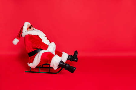 Full length body size view of nice attractive fat bearded man riding traveling on sledge tour trip tourism wintertime vacation having fun isolated on bright vivid shine red backgroundの写真素材