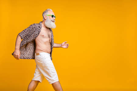 Copyspace photo of old man moving torward something during holiday abroad while isolated with yellow backgroundの写真素材
