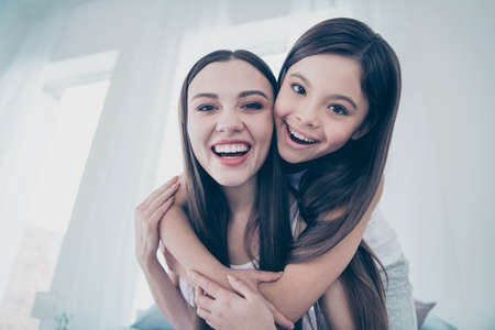 Close-up portrait of two nice beautiful attractive lovely charming cute cheerful cheery funny funky glad carefree kind people cuddling spending free time weekend in light white interior roomの写真素材