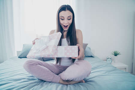 Close-up portrait of her she nice-looking beautiful attractive lovely charming cute feminine delighted cheerful cheery girl opening romance box celebrate sitting on sheets in white light interior roomの写真素材