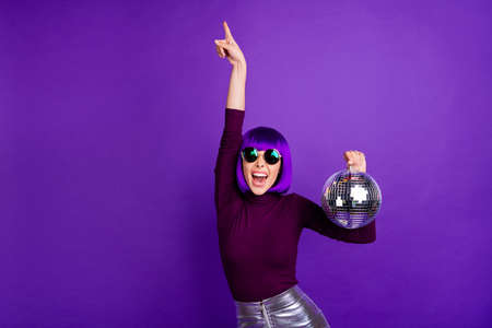 Portrait of cheerful girl with eyewear eyeglasses raising hands wearing turtleneck silver skirt isolated over purple violet backgroundの写真素材